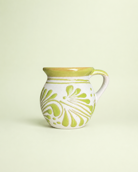Ceramic mug with green floral patterns on a light beige background
