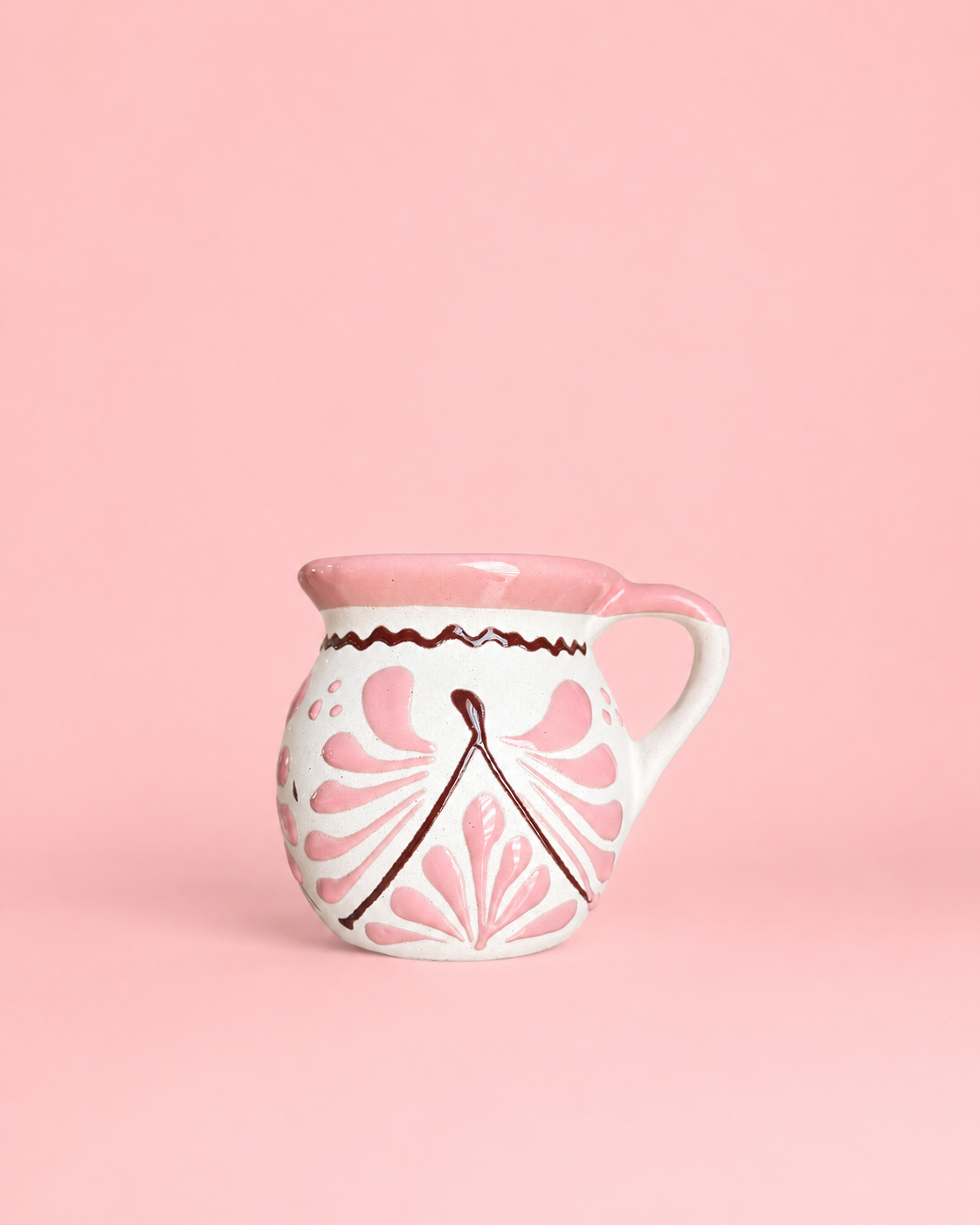 White ceramic mug with pink floral patterns on a pink background