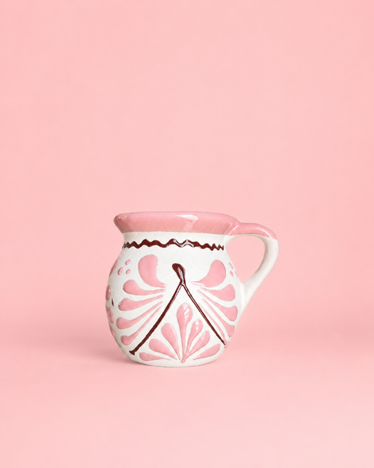 White ceramic mug with pink floral patterns on a pink background