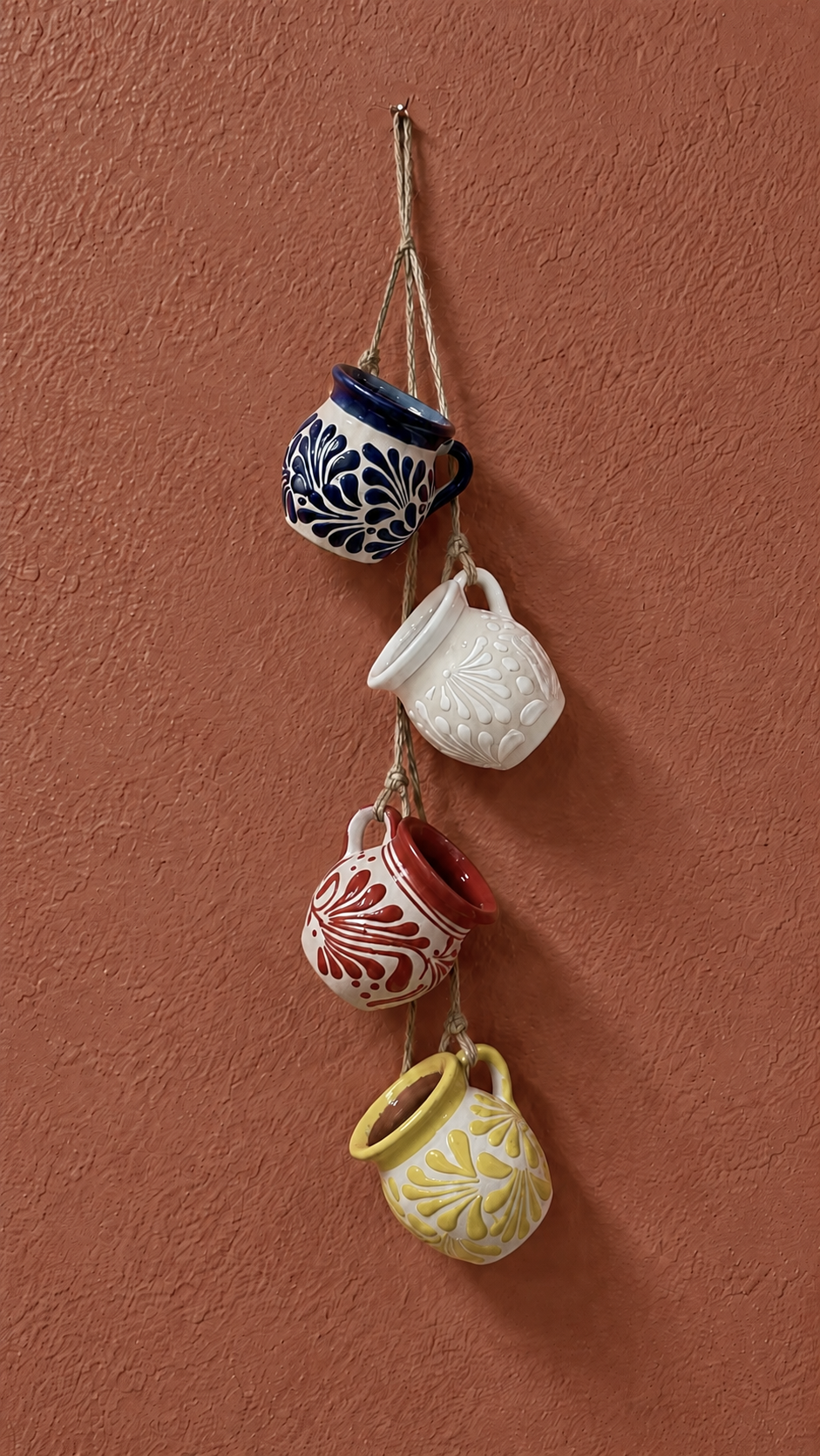 Set of colorful ceramic pots hanging on a terracotta wall
