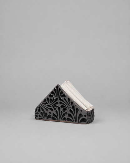 Triangular ceramic napkin holder  with intricate design on a gray background