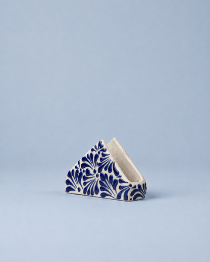 A small triangular ceramic container with a blue and white floral pattern, set against a solid light blue background.