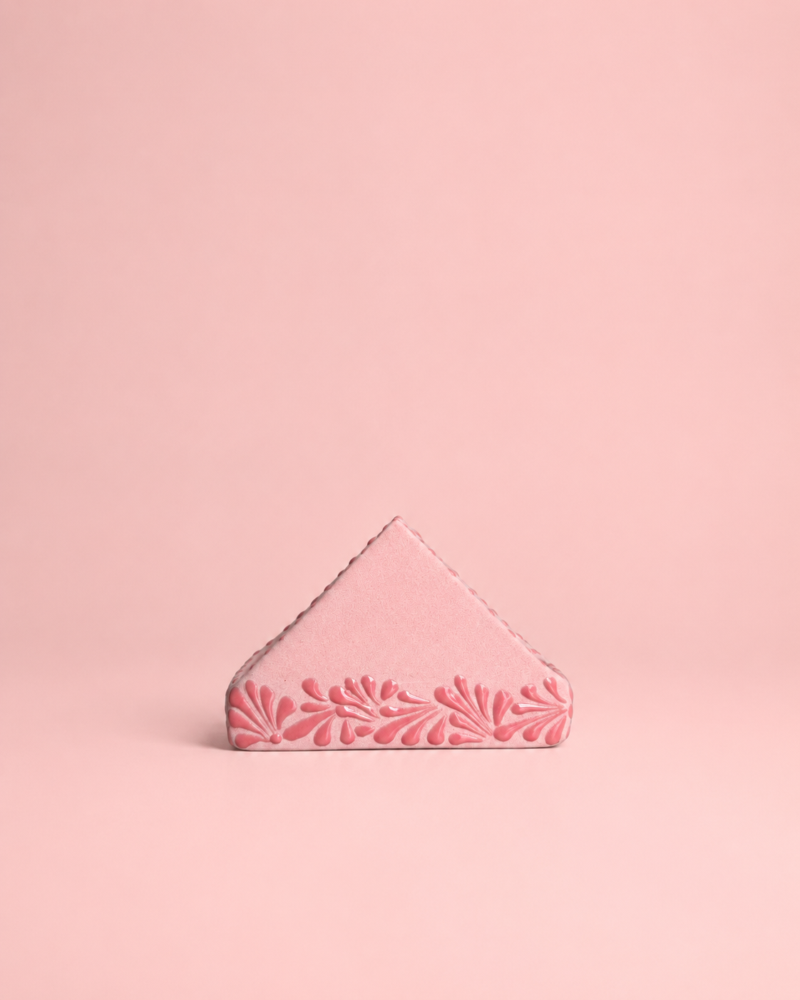 Pink triangular napkin holder  with floral design on a pink background