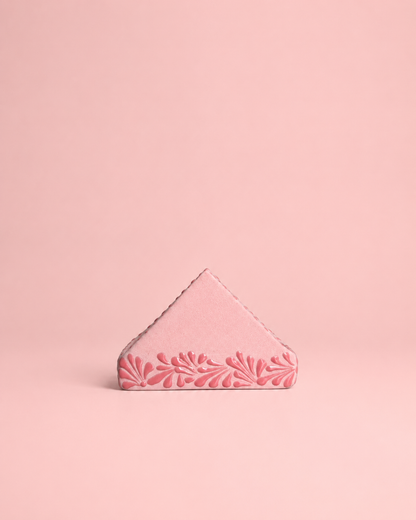 Pink triangular napkin holder  with floral design on a pink background