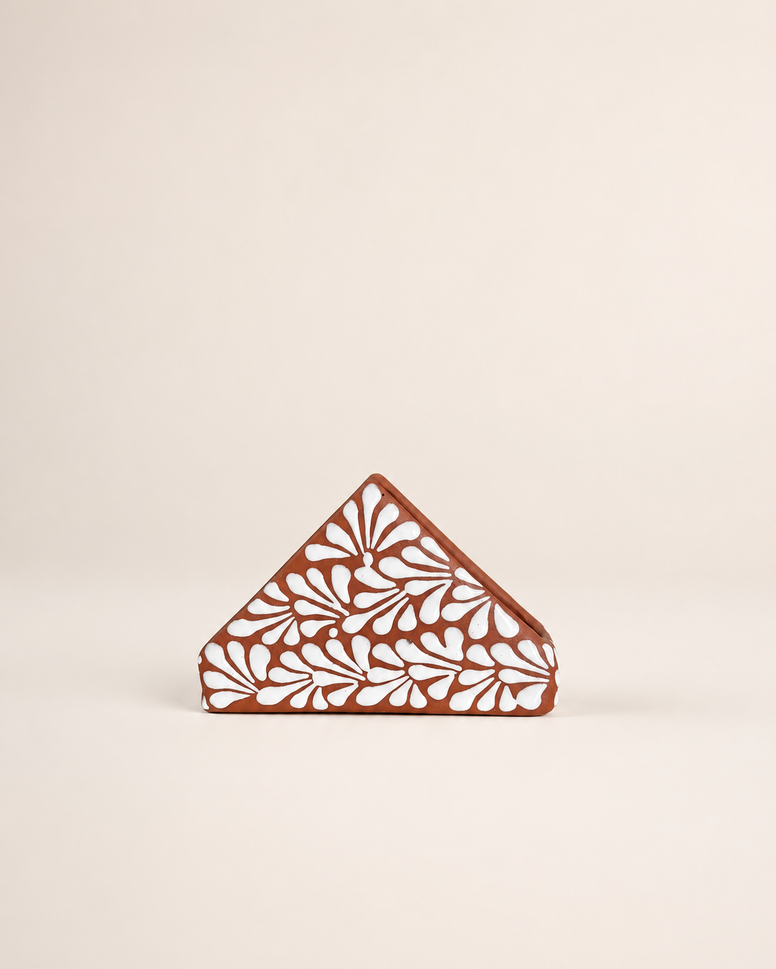 Triangular napkin holder  with floral cutout design on a beige background