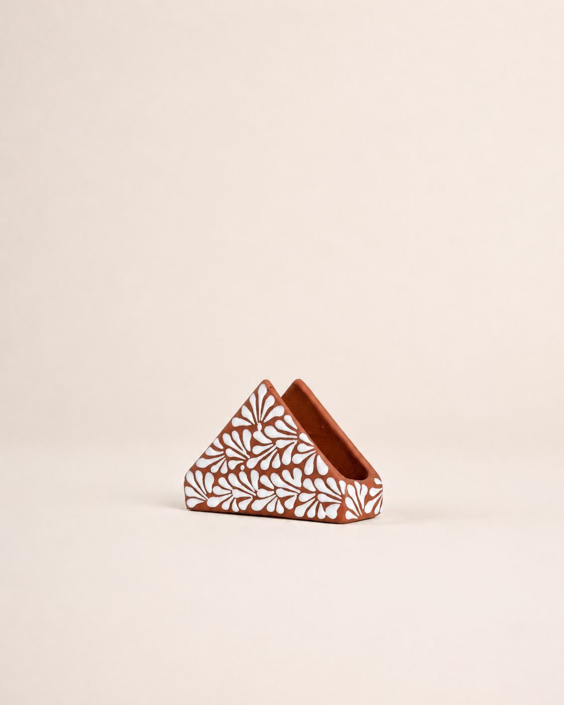 Decorative triangular brown napkin holder with white pattern on a beige background