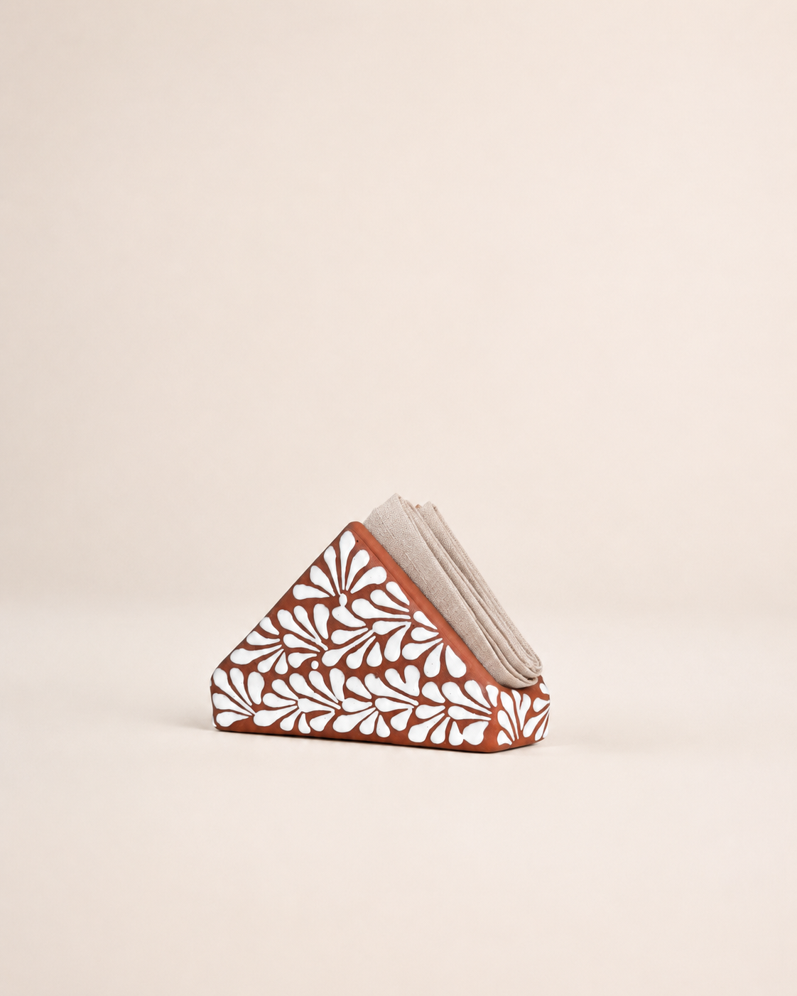 Triangular ceramic napkin holder  with floral patterns on a beige background
