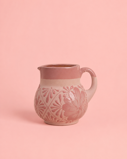 Pink ceramic pitcher with floral patterns on a pink background