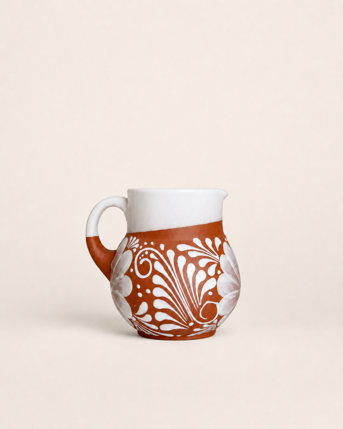 Ceramic pitcher with white handle and decorative brown pattern on a beige background