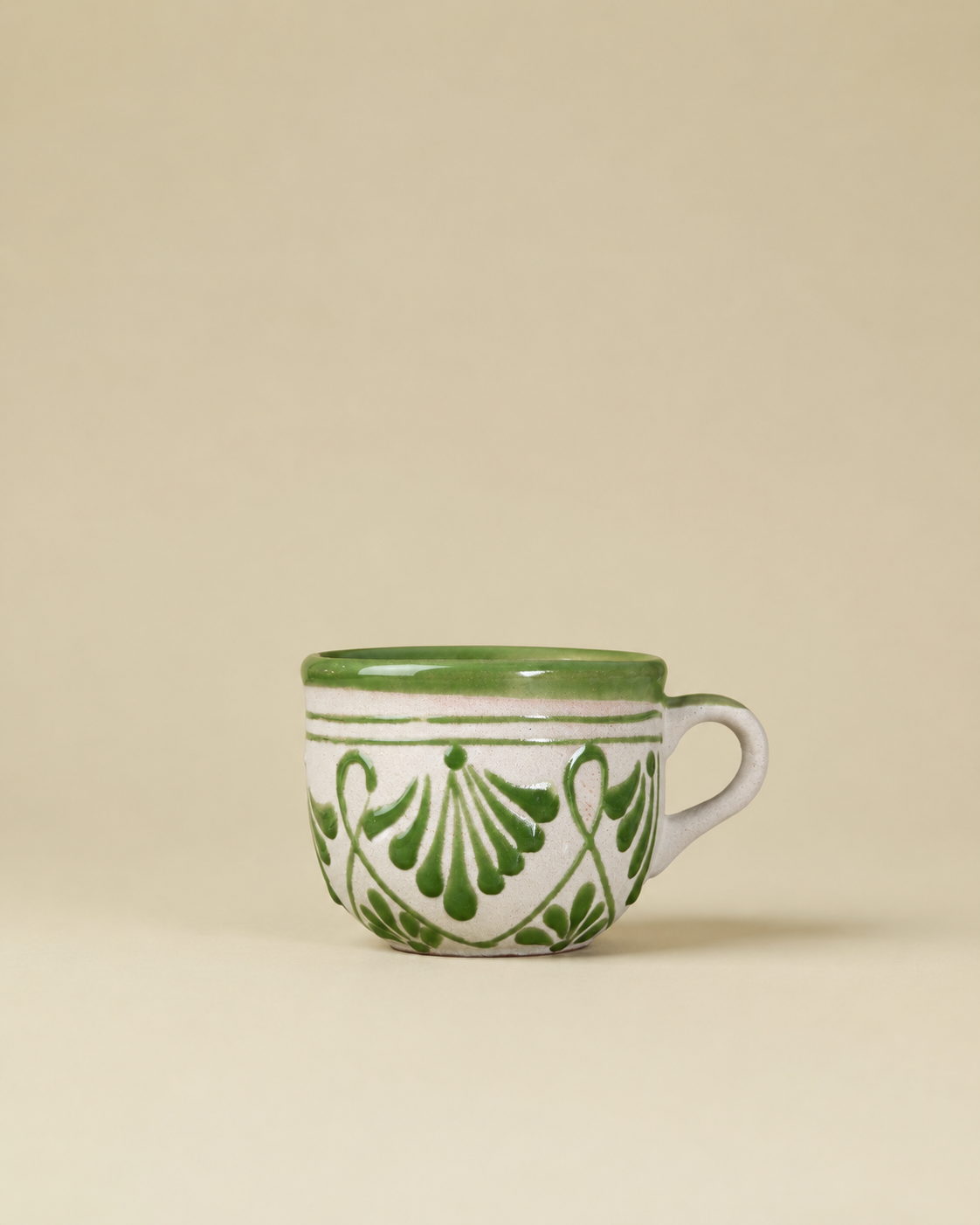 Ceramic mug with green floral patterns on a beige background