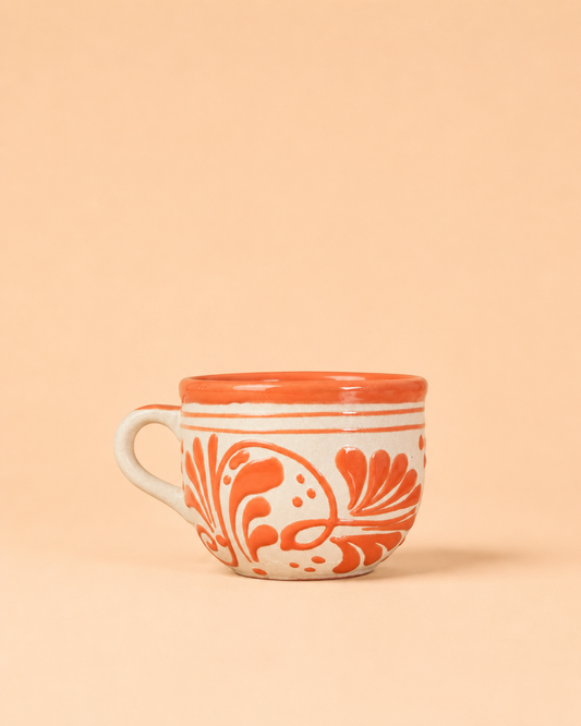 Ceramic mug with orange floral patterns on a beige background
