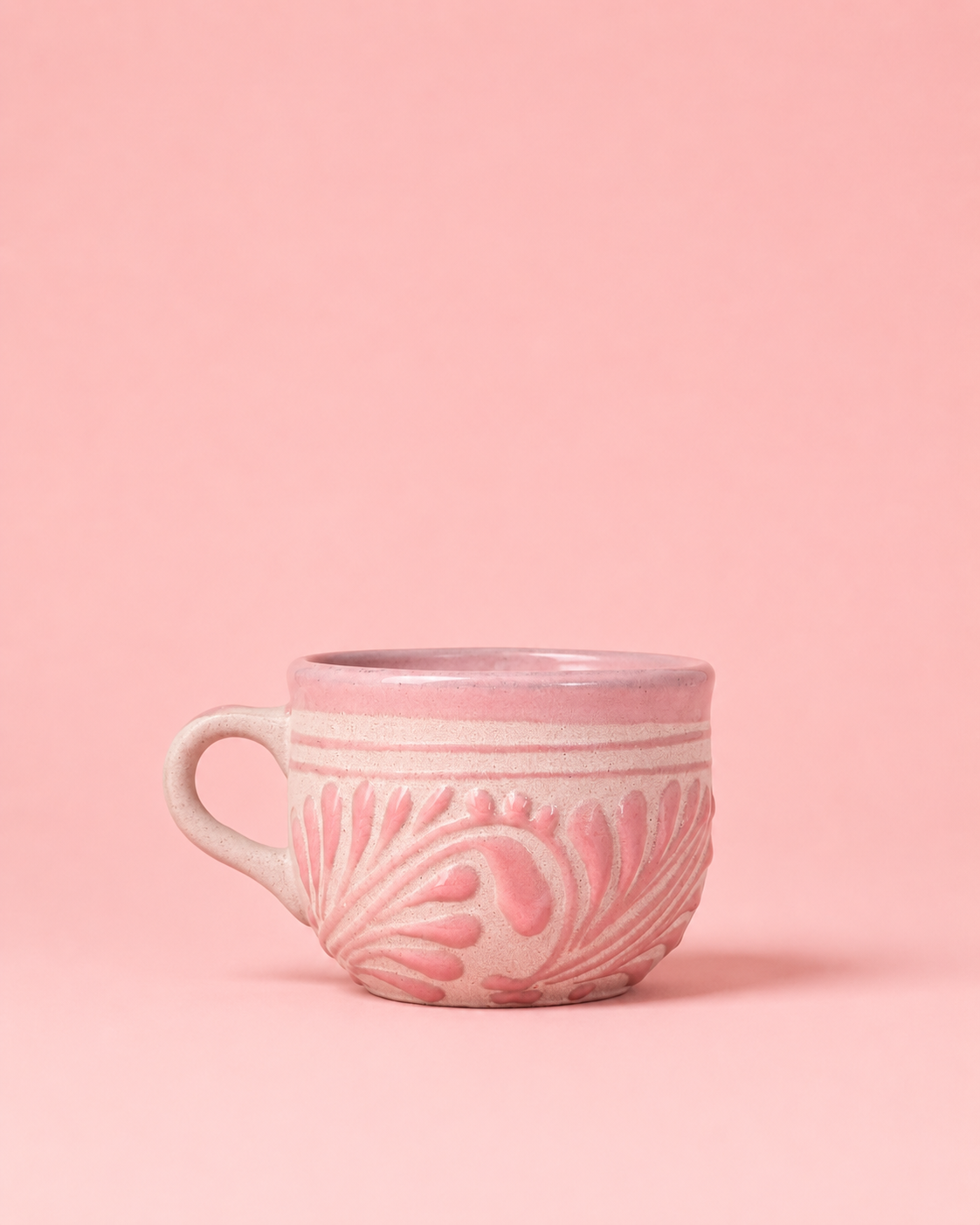 Pink ceramic mug with decorative patterns on a pink background