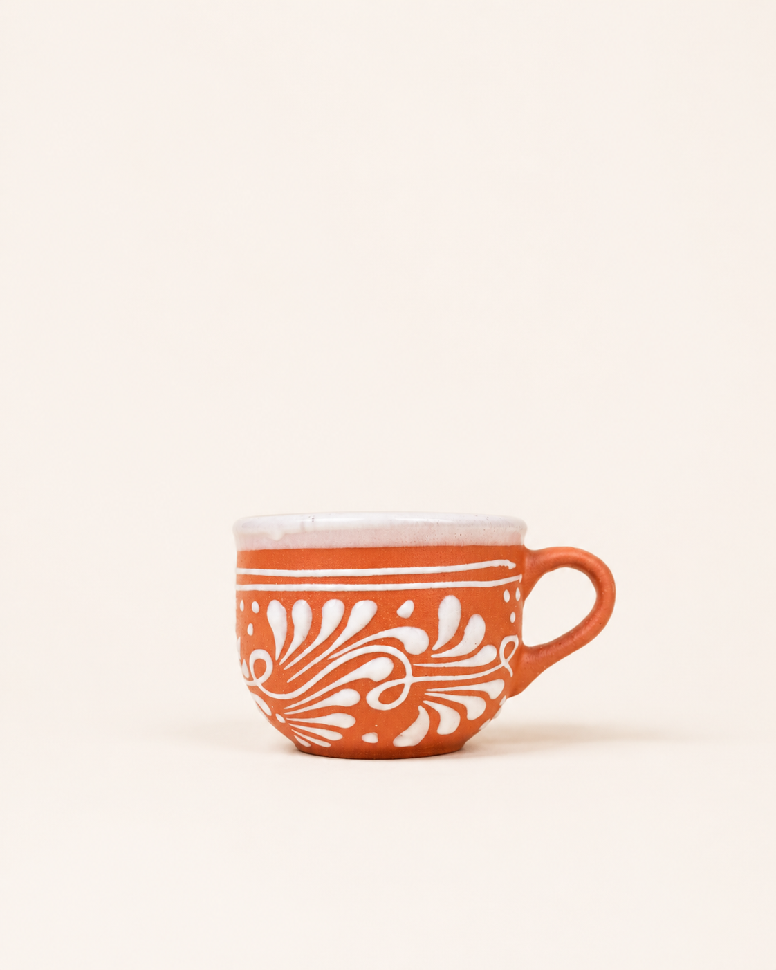 Brown ceramic mug with white floral patterns on a white background
