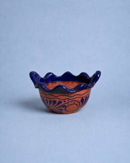 Ceramic bowl with blue rim and orange interior on a light gray background