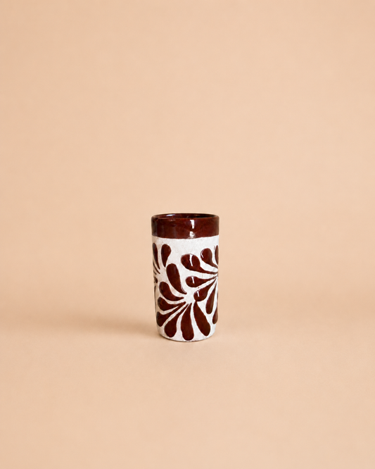 Ceramic shot glass with brown leaf pattern on a beige background