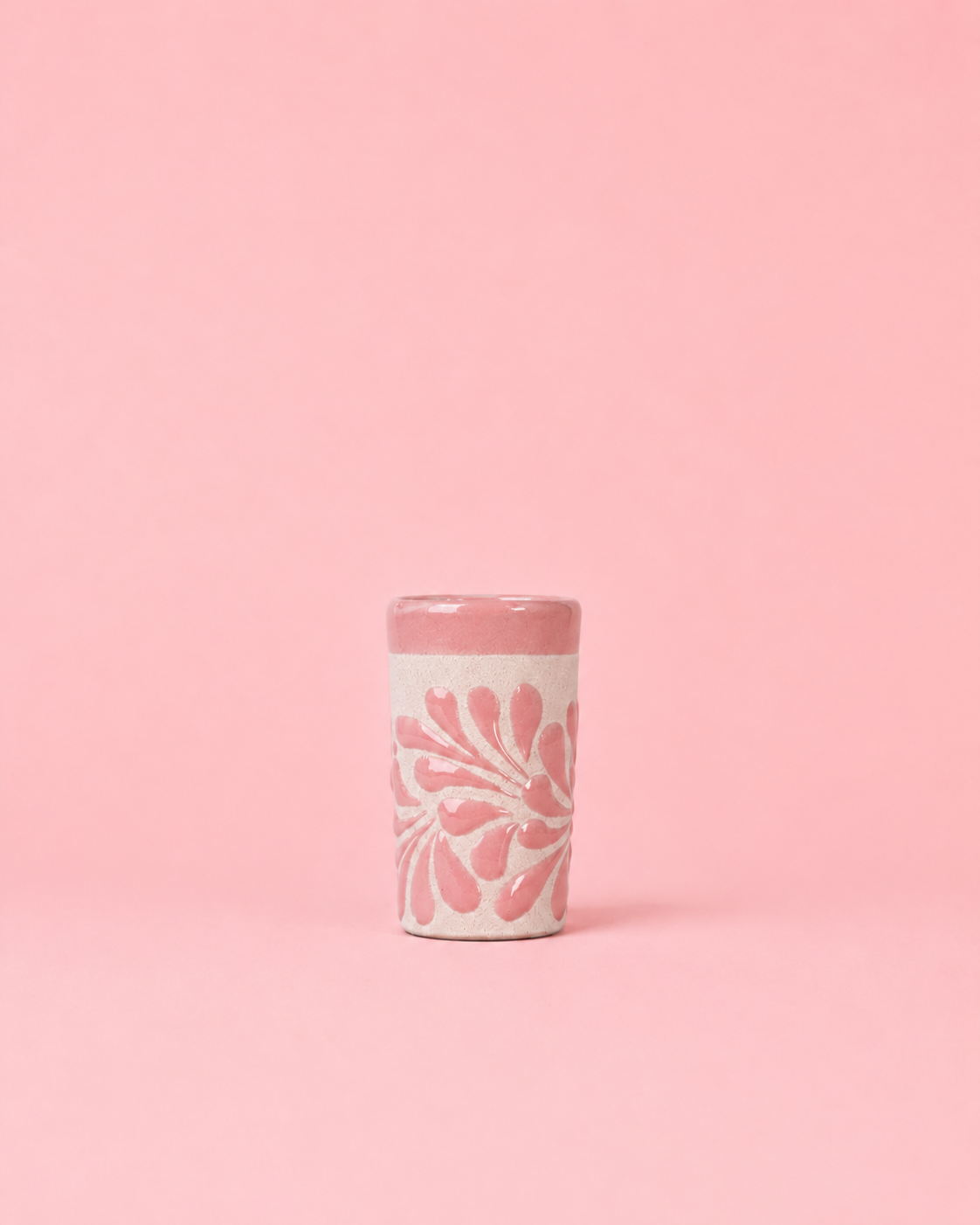Pink shot glass with floral design on a pink background