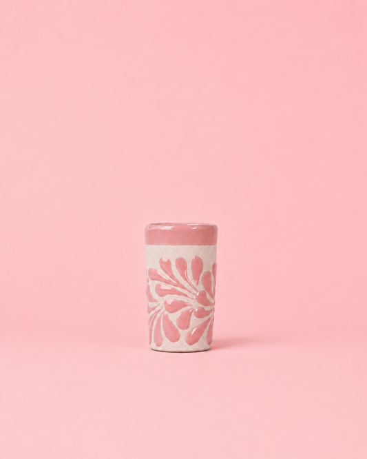 Pink shot glass with floral design on a pink background