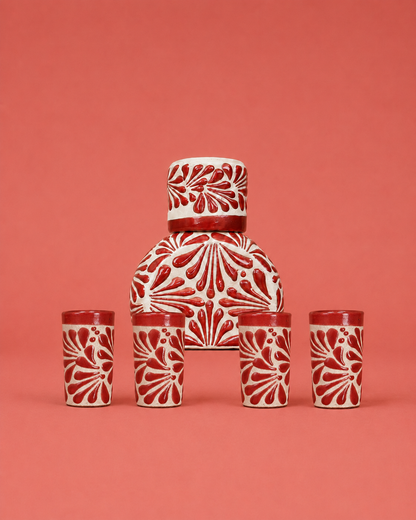 Ceramic set with a central jar and four matching cups on a red background