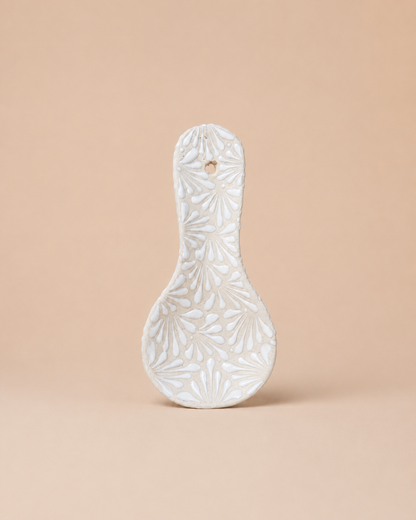Decorative ceramic spoon rest with floral patterns on a beige background
