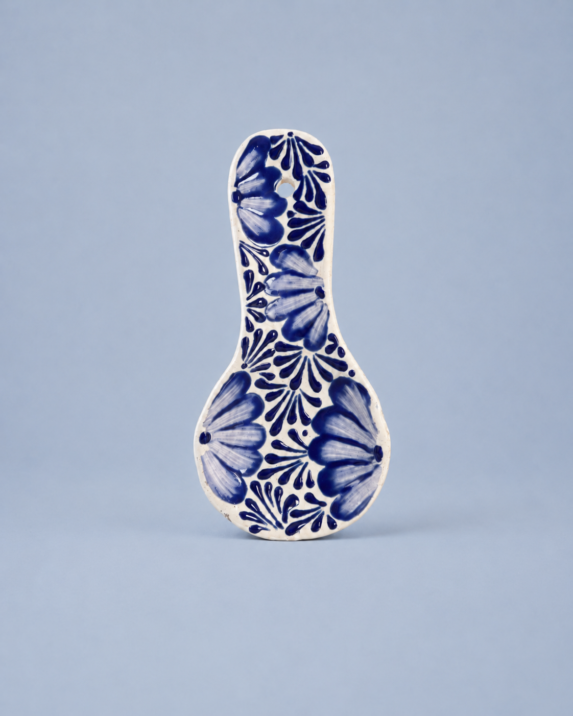 Ceramic spoon rest with blue floral pattern on a light blue background