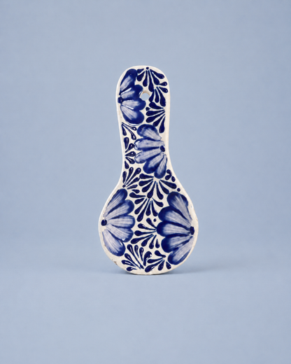 Ceramic spoon rest with blue floral pattern on a light blue background