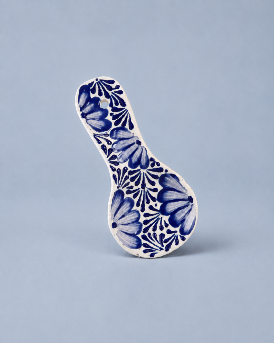 Ceramic spoon rest with blue floral pattern on a light gray background