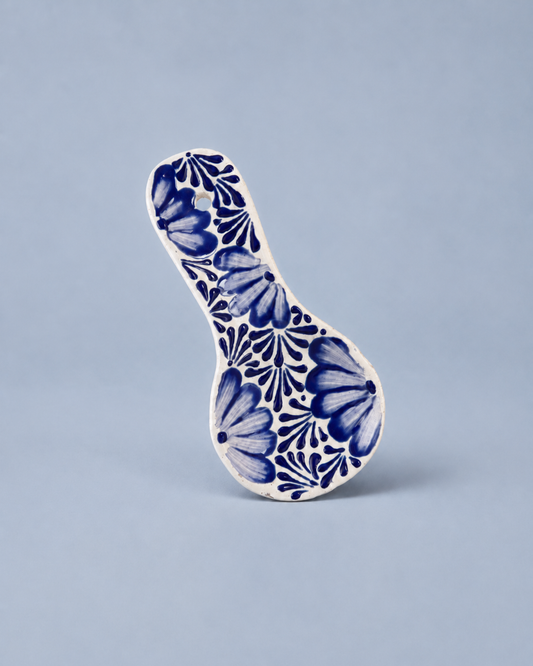 Ceramic spoon rest with blue floral pattern on a light gray background