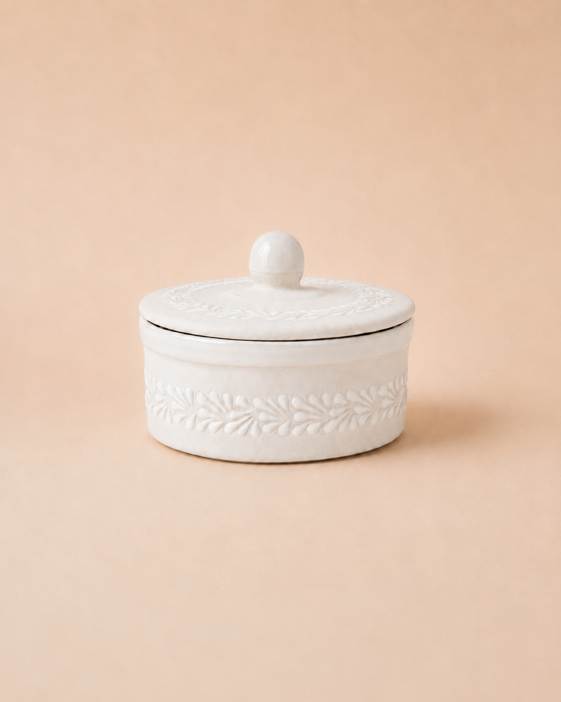 White ceramic tortilla warmer with lid on a beige background