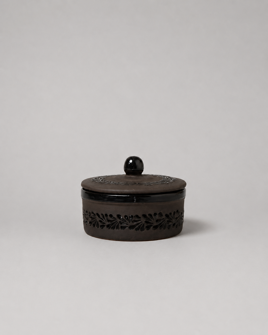 Black decorative container with lid on a light gray background
