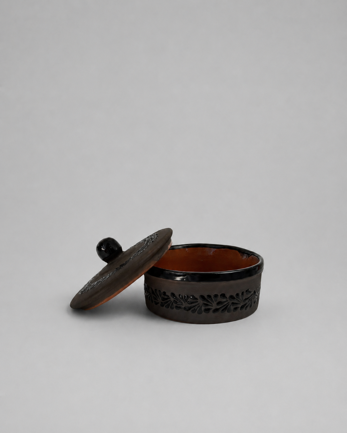 Black decorative container with a lid on a light gray background