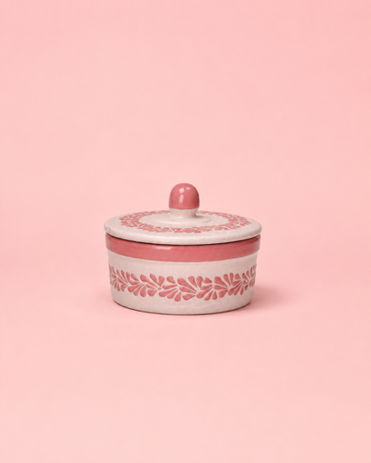 Pink ceramic container with white lid on a pink background