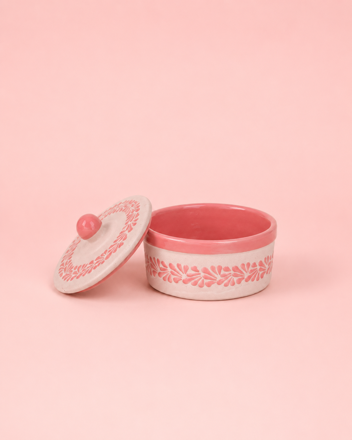 Pink ceramic container with lid on a pink background