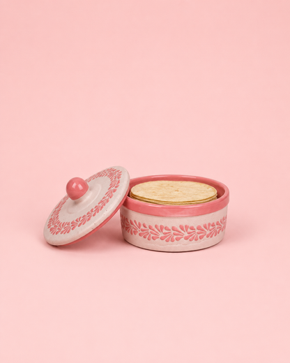 Pink ceramic container with lid on the side and tortillas inside on a pink background