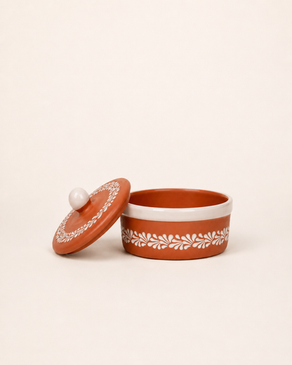 Terracotta container with white lid and decorative patterns on a beige background