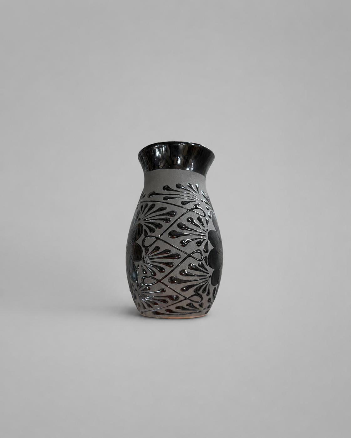 Ceramic vase with black and gray decorative patterns on a light gray background
