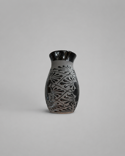 Ceramic vase with black and gray decorative patterns on a light gray background