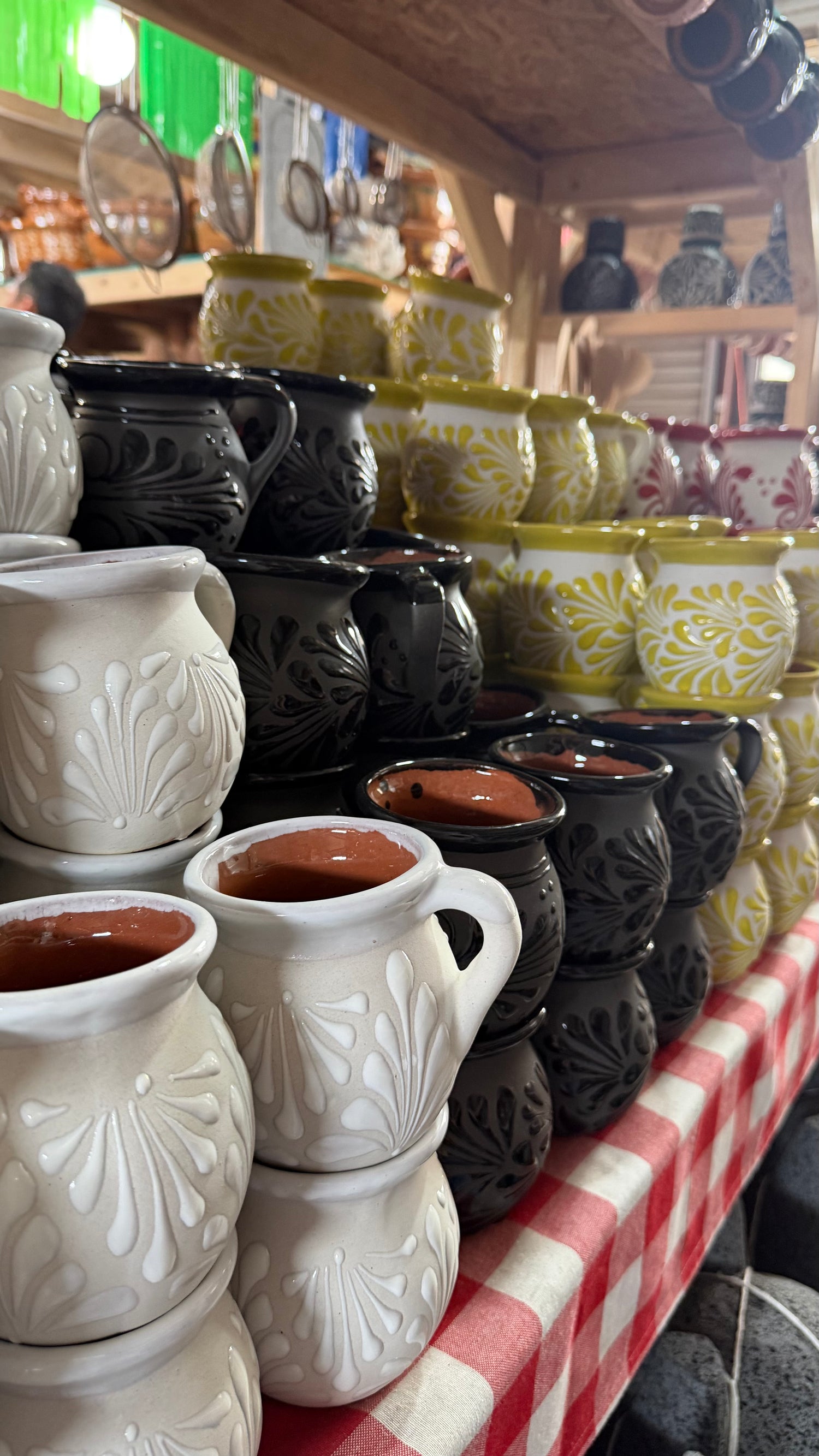 Display of ceramic pots and vases on a table with a checkered tablecloth.